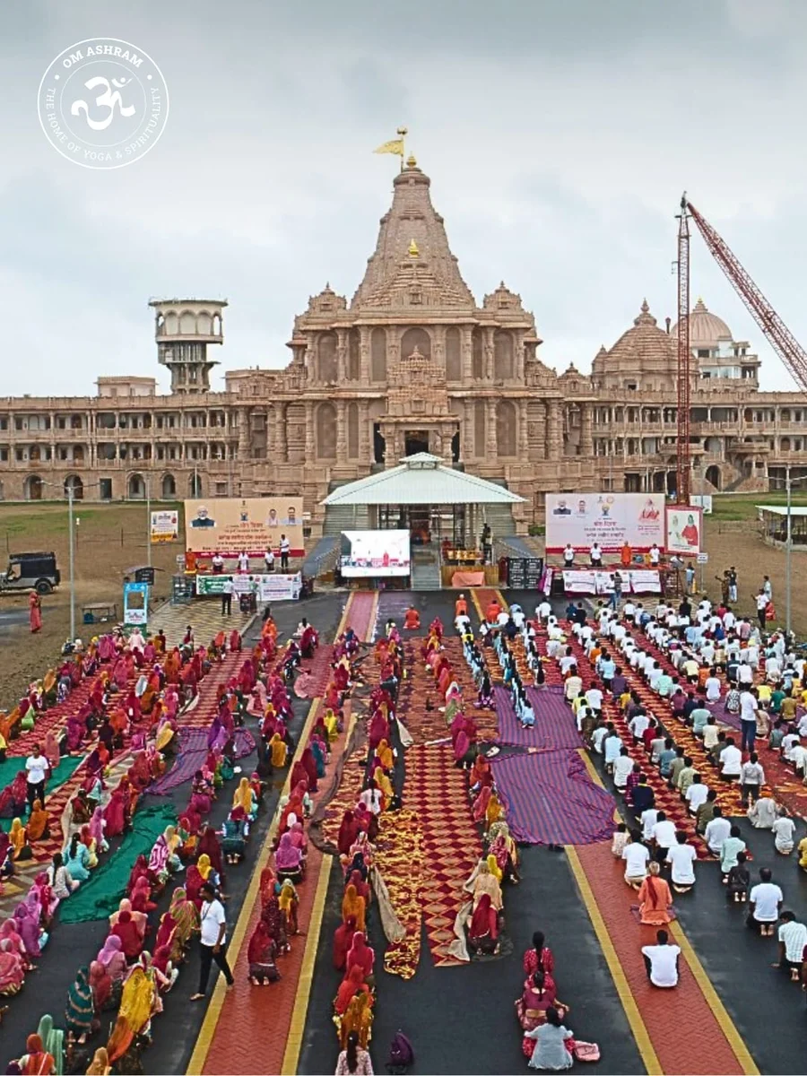 A large gathering of people practicing yoga together in front of the Shiva Temple at OM Ashram during last year's International Yoga Day.